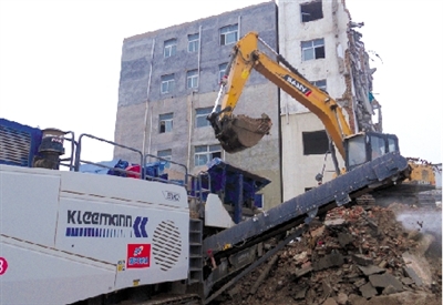 挖掘機(jī)向可移動式破碎機(jī)喂料槽填送大塊建筑垃圾